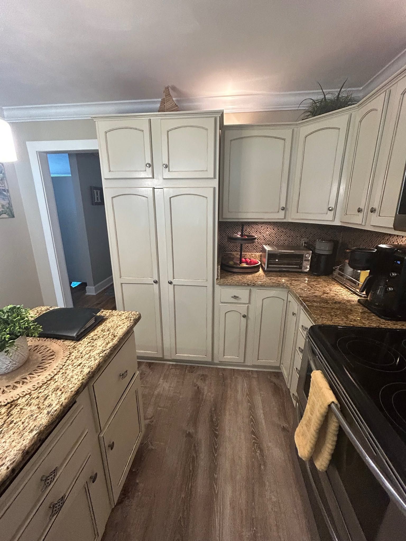 Small kitchen with white cabinets, dark countertops, and a black stove under warm lighting.