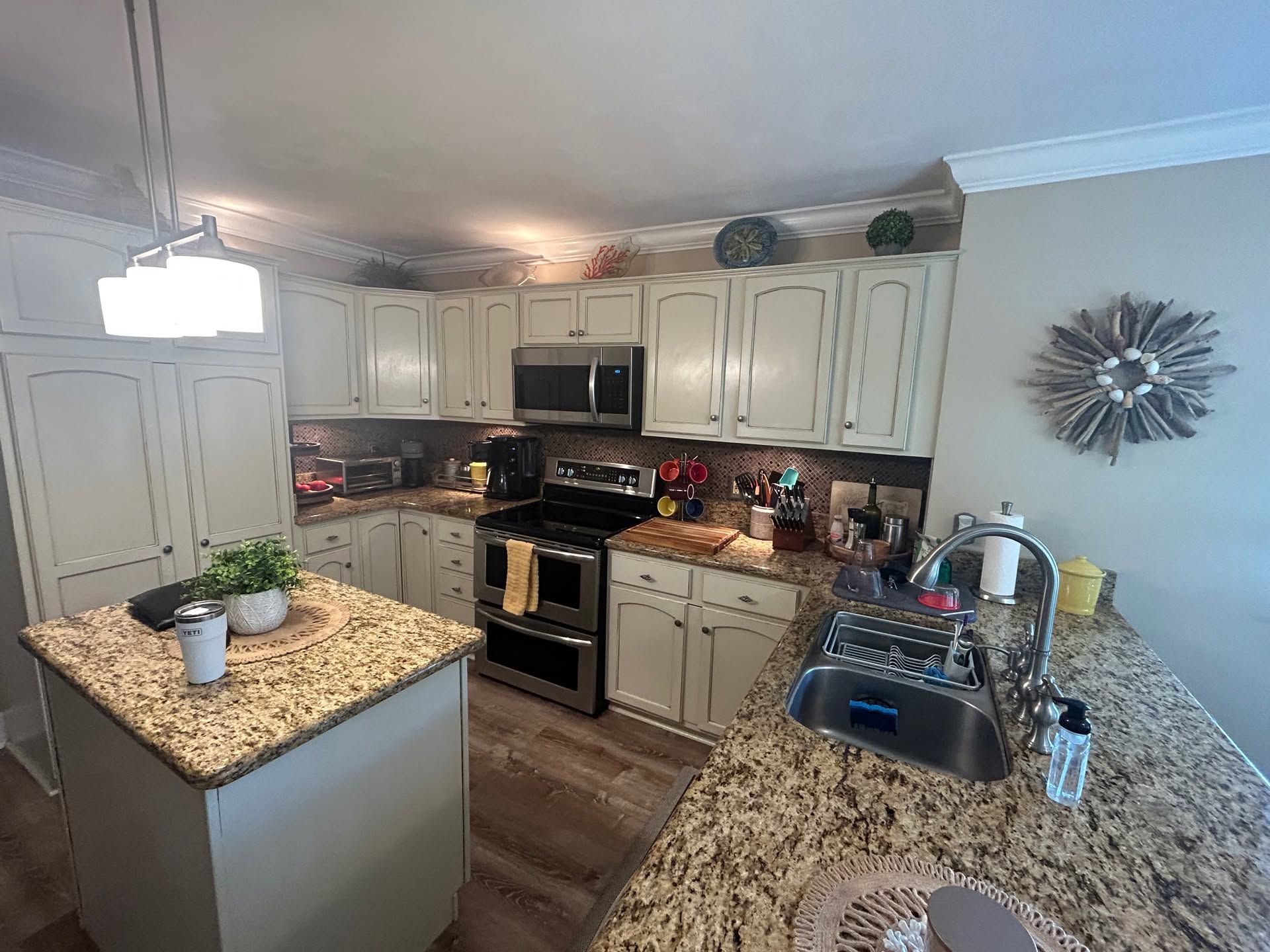 Modern kitchen with white cabinets, granite counters, stainless appliances, and a central island.