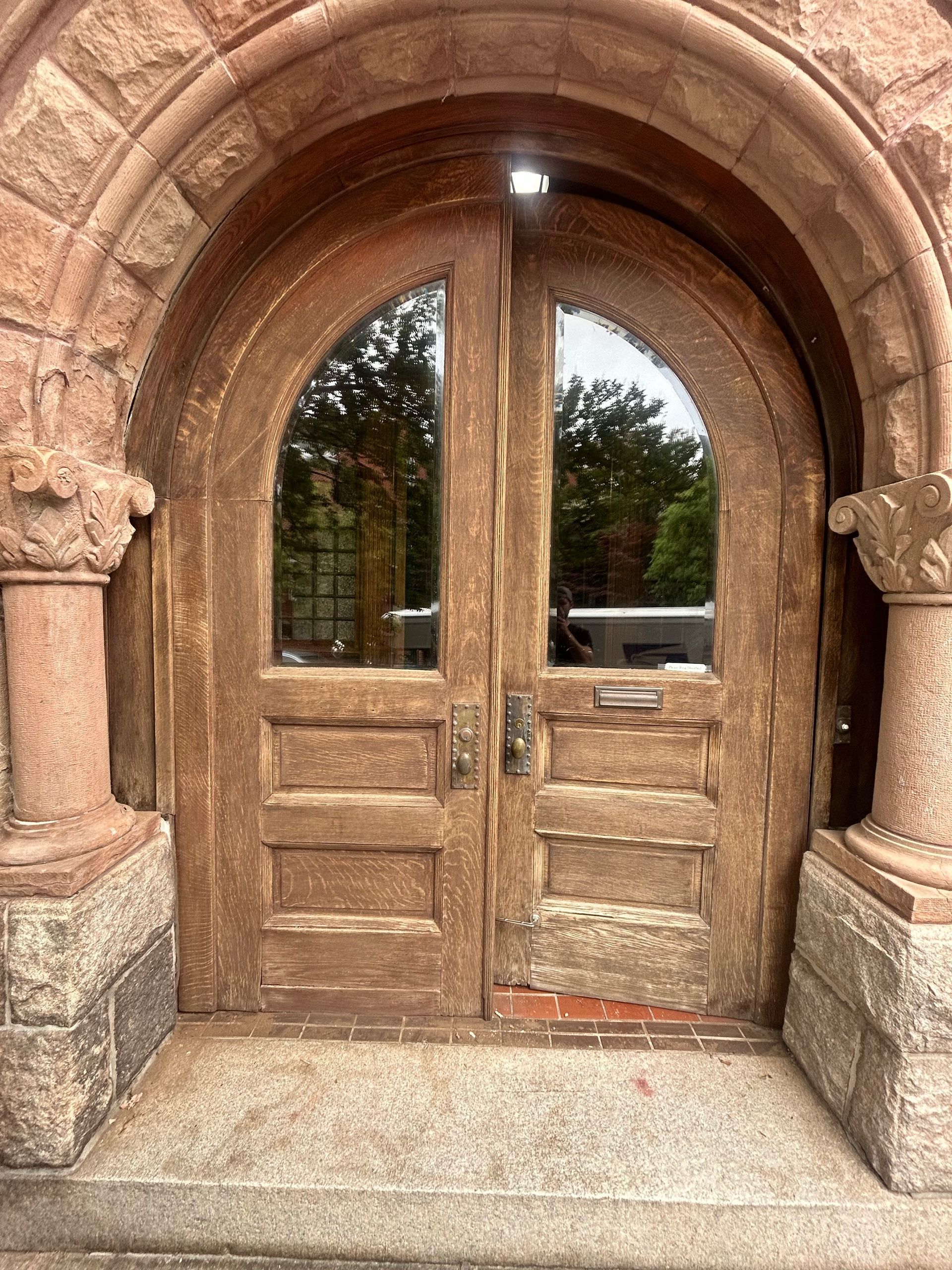 Stone arched wooden double door with glass panes and steps leading up to it