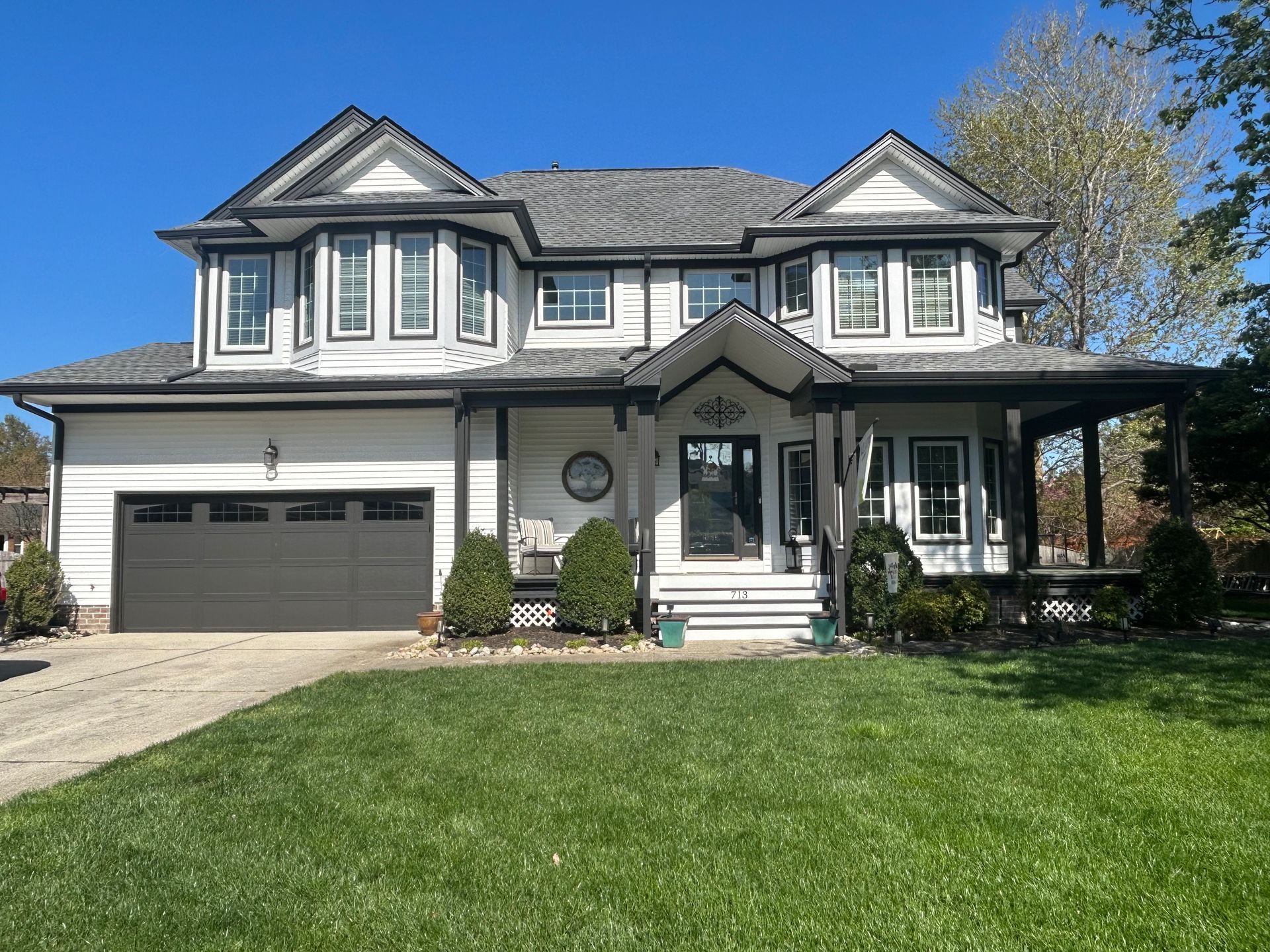 Two-story gray house with attached garage and green lawn on a sunny day