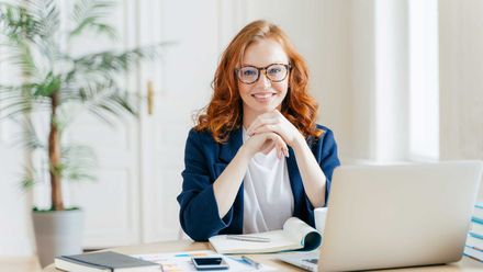 a woman is sitting at a desk in front of a laptop computer .