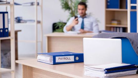 a man is sitting at a desk in an office talking on a cell phone .