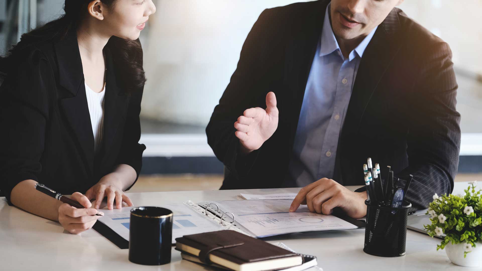 a man and a woman are sitting at a table talking to each other .