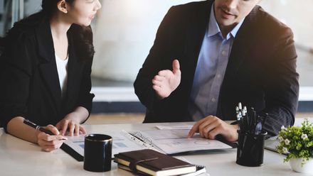 a man and a woman are sitting at a table talking to each other .