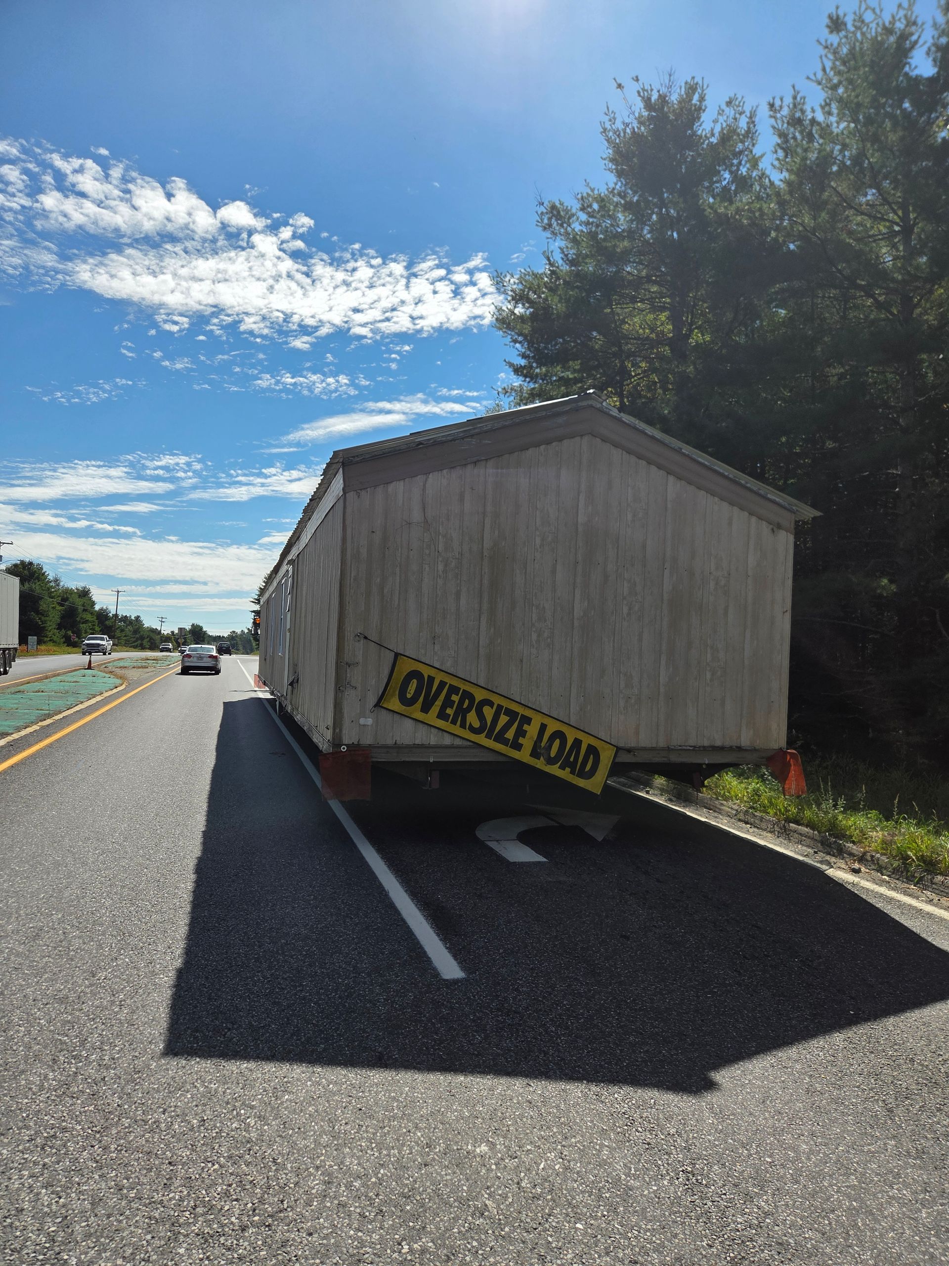 A mobile home being transported on a highway, marked with a yellow 