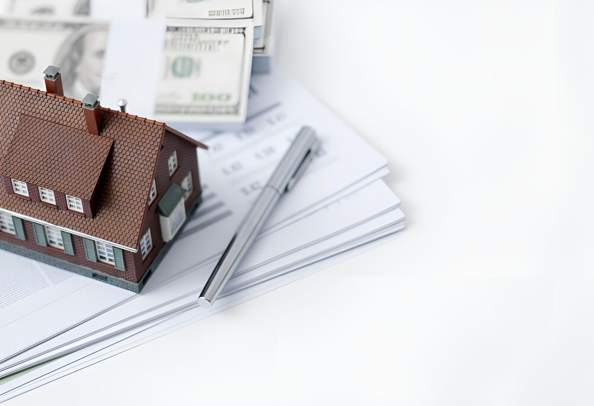 A Model House is Sitting on Top of a Pile of Papers Next to a Pen and Money — Bradley J Bragg - Solicitor in Atherton, QLD