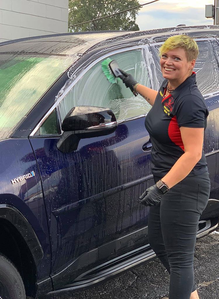 certified detailing technician working at Fresh Start Detail & Ceramic Coating in Beaverton smiling at the camera whilst washing a car