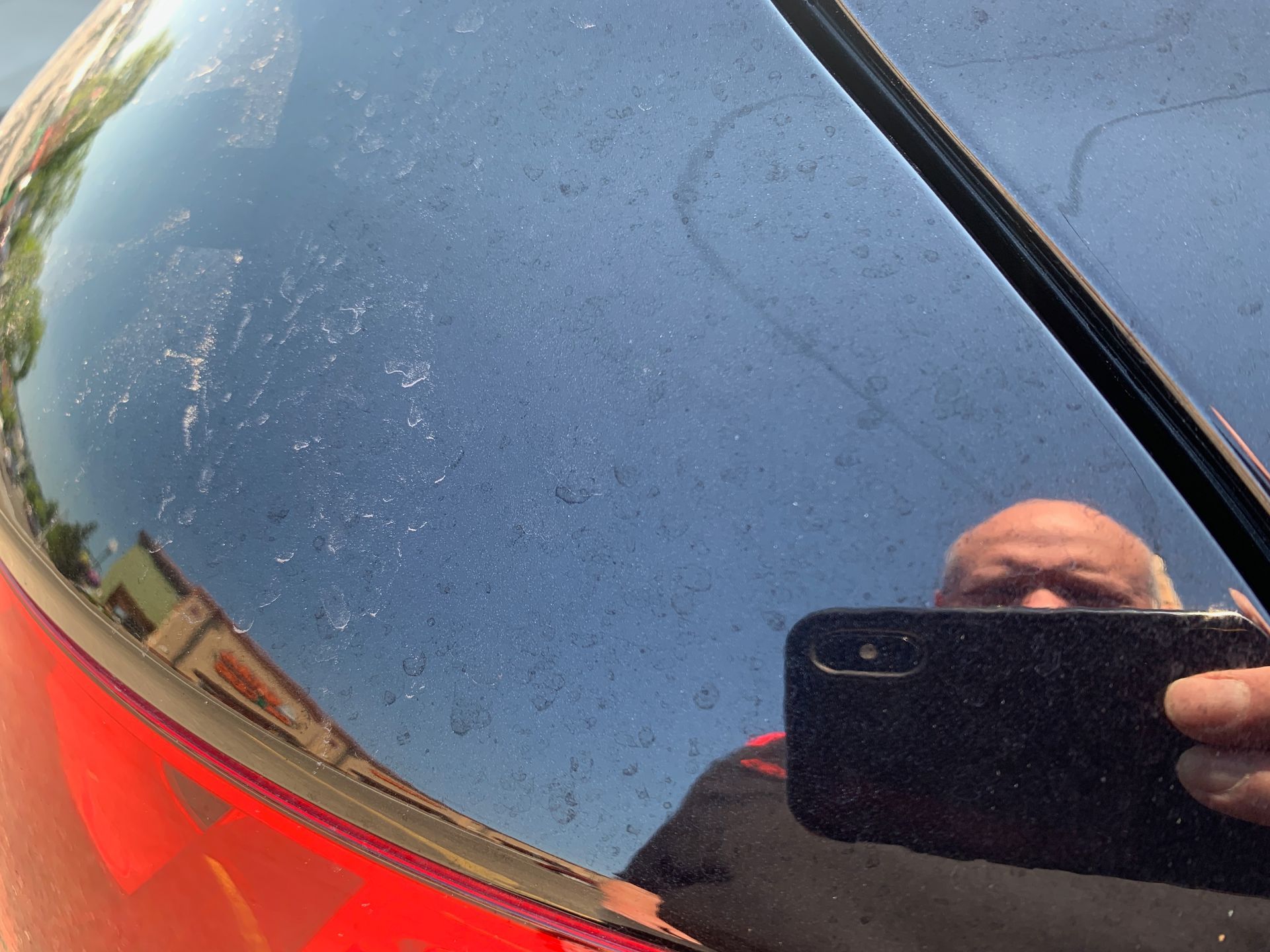 water spots on a black car prior to chemical decontamination process
