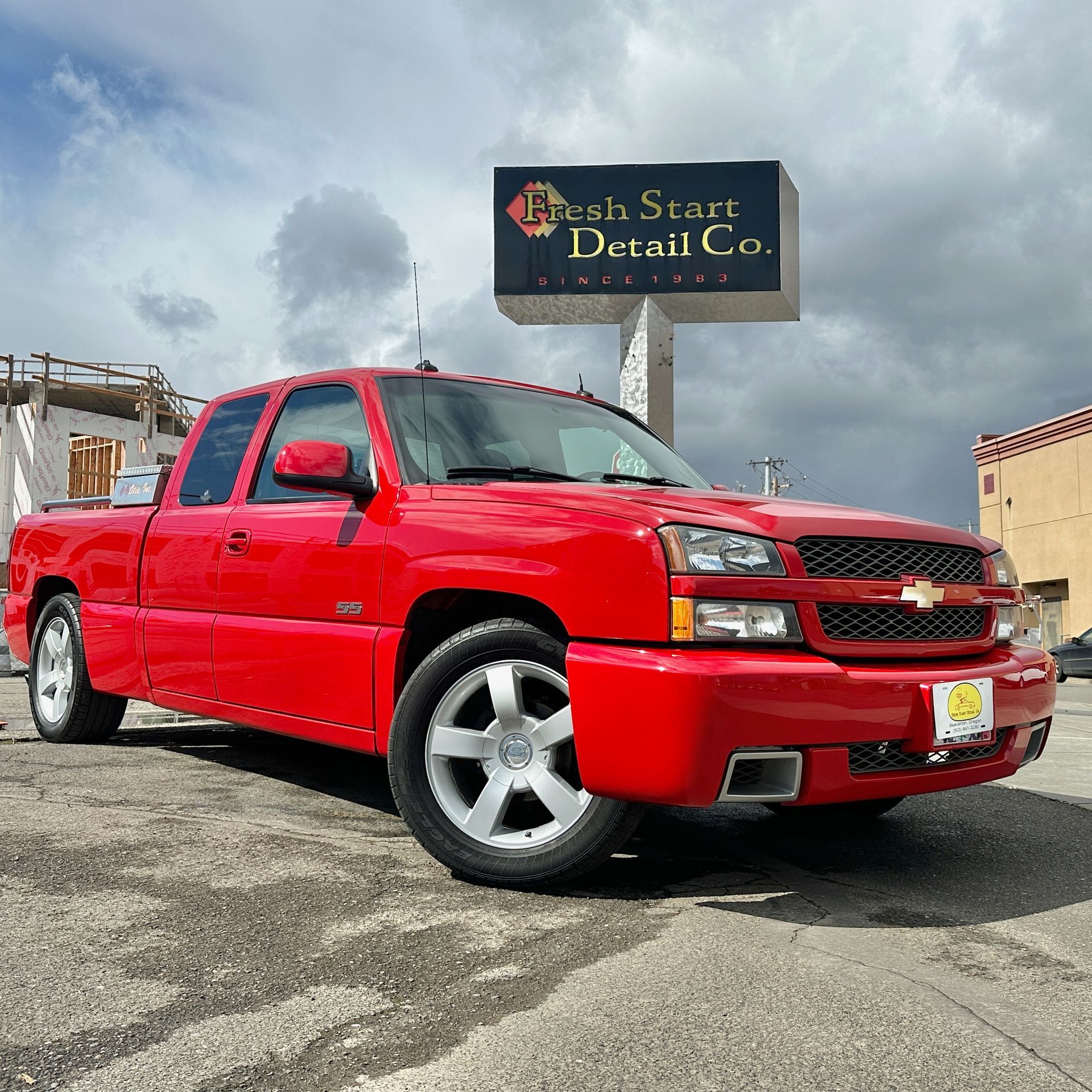 Red Chevrolet Silverado pickup truck parked outside a business with a sign that reads