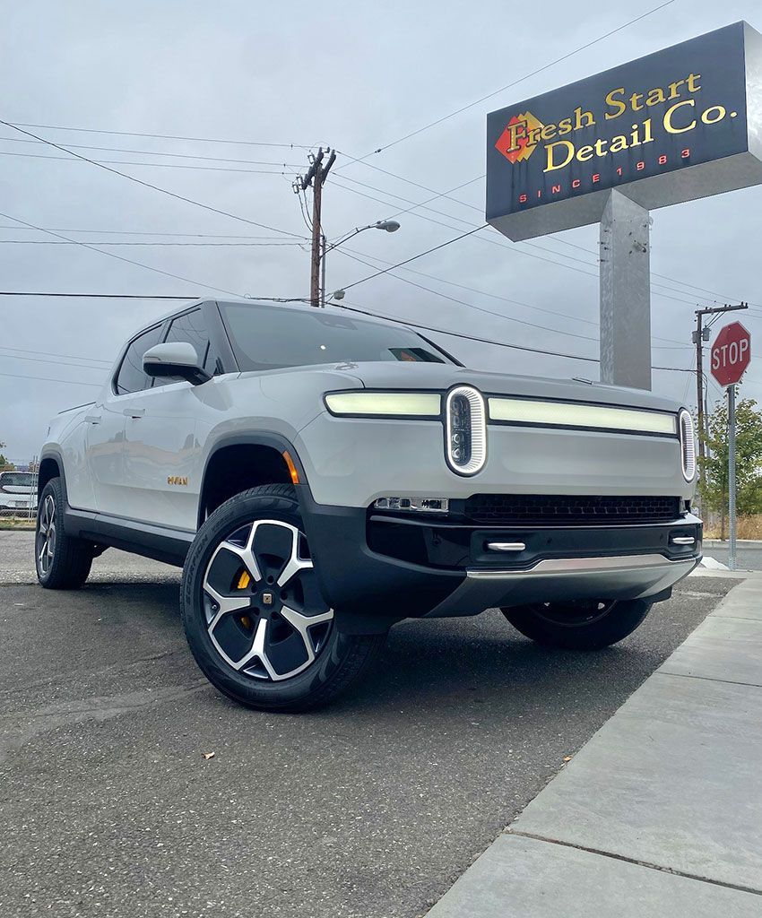 Silver Rivian SUV parked in front of a 