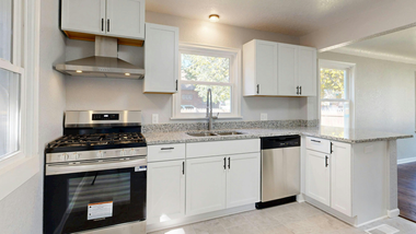 White kitchen with stainless steel appliances, granite countertops, and white cabinets.