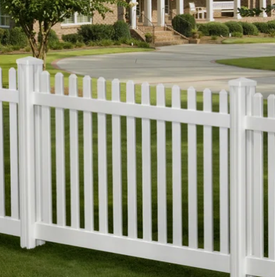 White vinyl picket fence in front of a suburban lawn and driveway