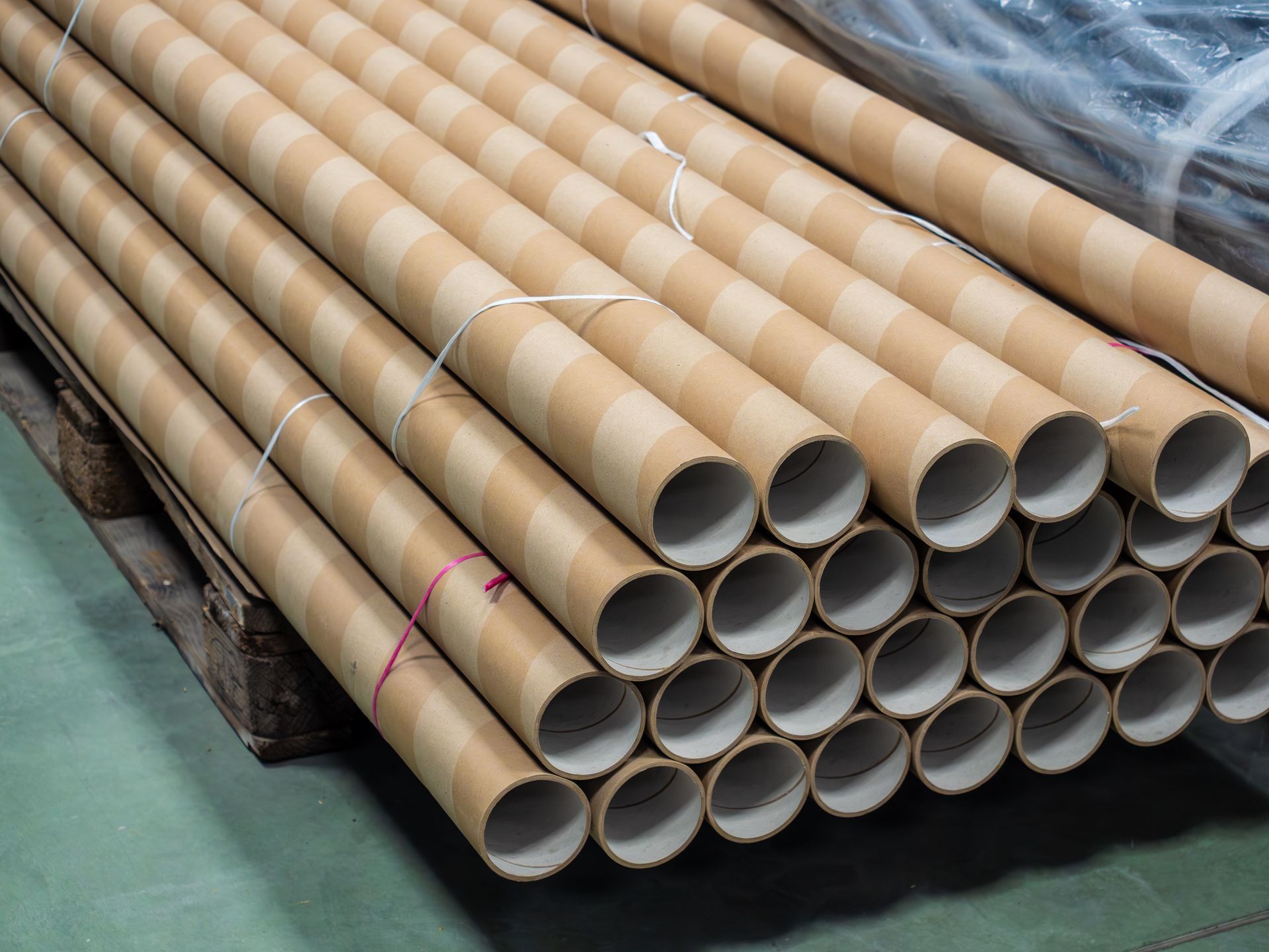 Multiple mailing tubes are neatly stacked on a wooden pallet used for shipping protection.