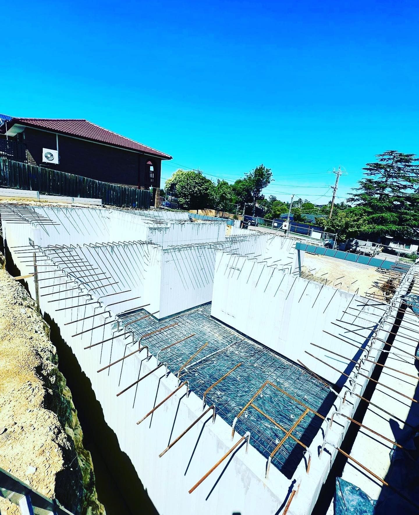 A large concrete wall is being built in front of a house.