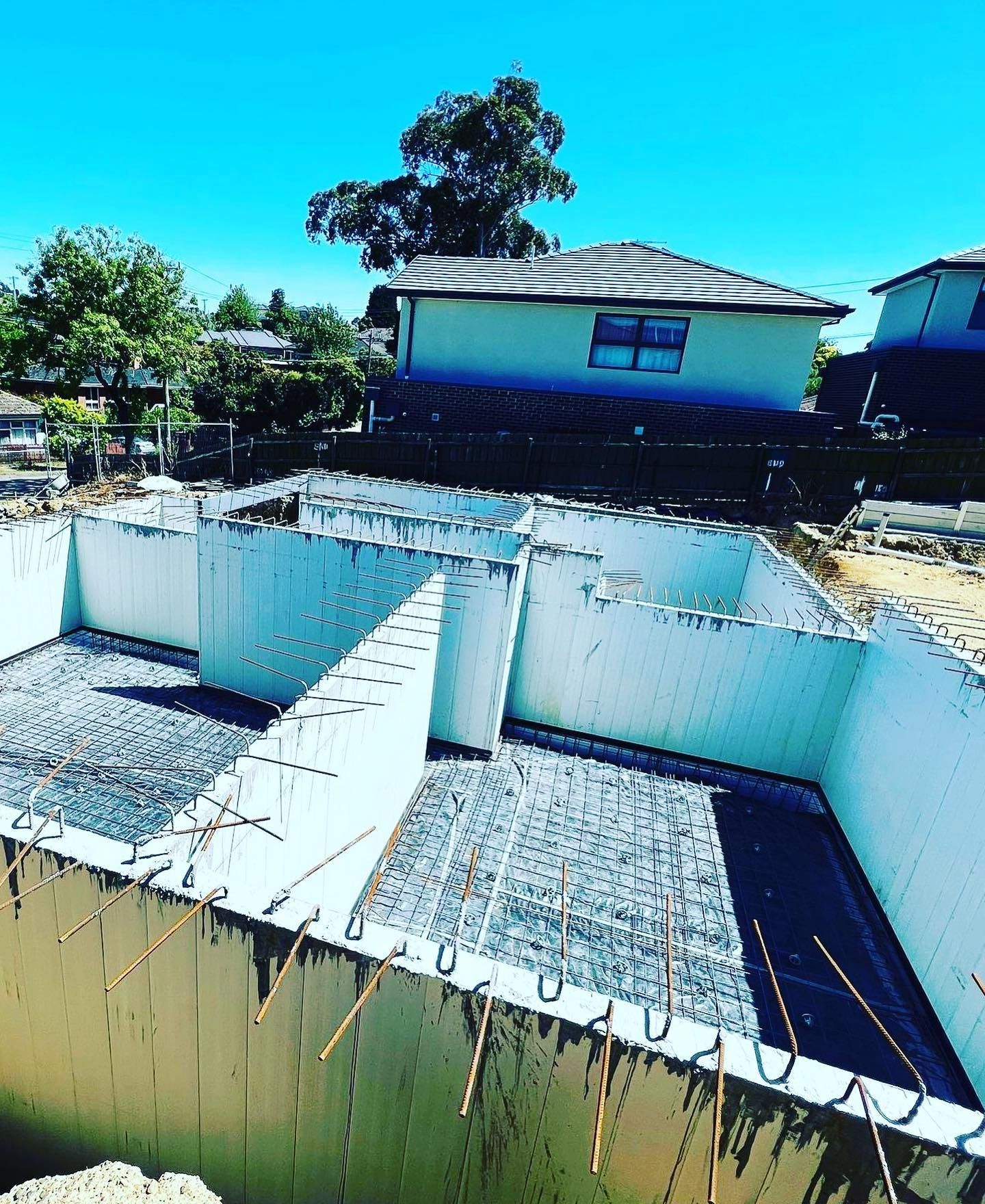 A building under construction with a house in the background