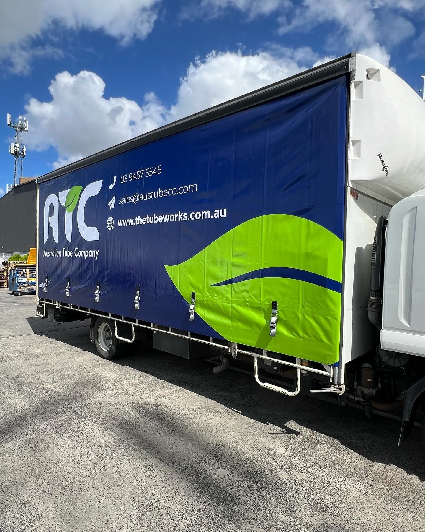 A large blue and green truck is parked in a parking lot.