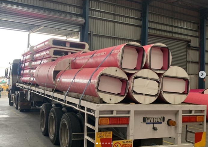 A truck is loaded with red pipes in a warehouse.