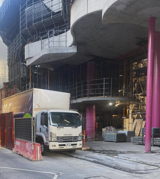 A white isuzu truck is parked in front of a building under construction