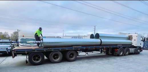 A man is standing on the back of a semi truck.