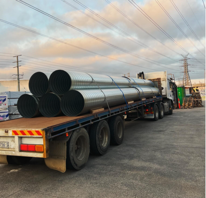 A truck is carrying a load of pipes on the back of it