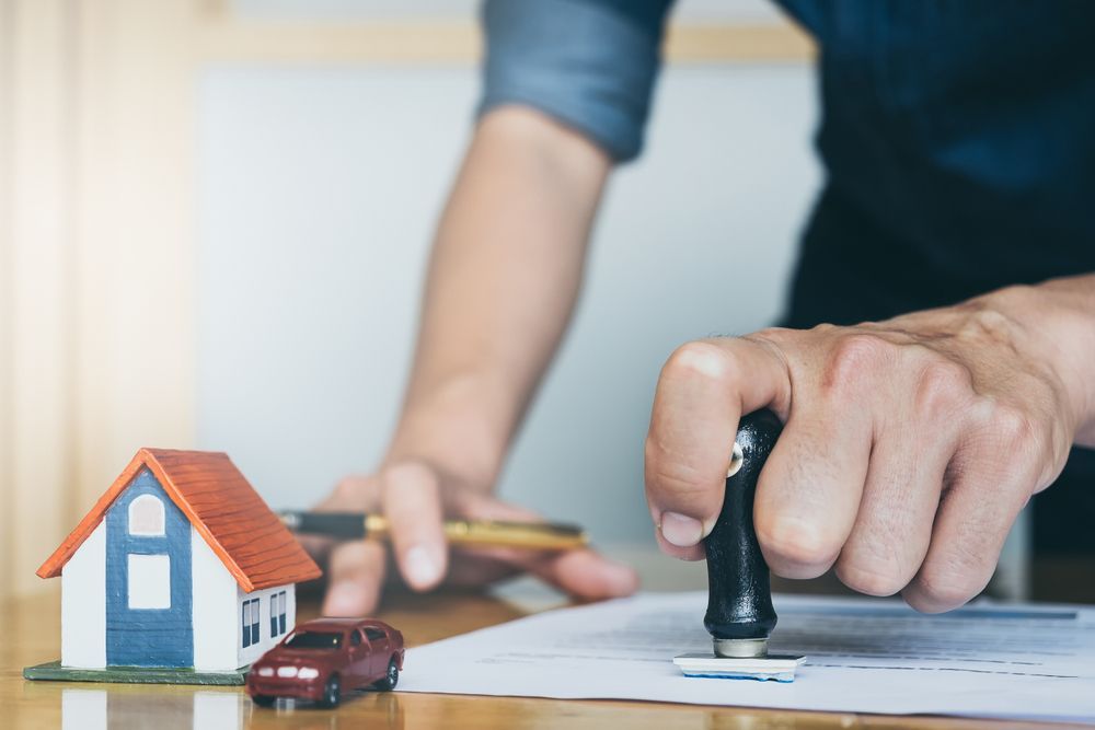 Person Stamps a Document, With a Toy House and Car Nearby — Trapski Family Law Geelong in Newtown, VIC