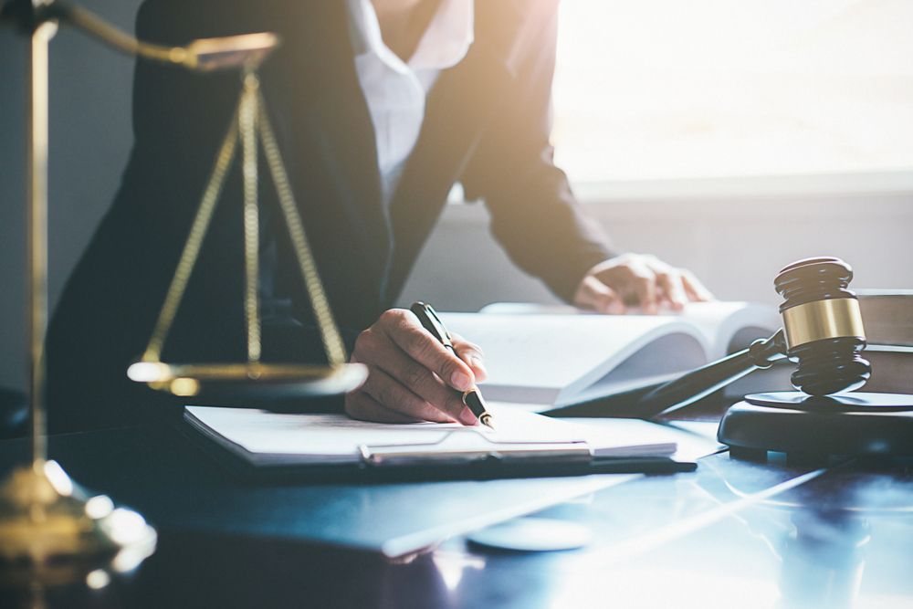 Lawyer Writing on a Clipboard, With Scales, a Gavel, and Books on a Desk — Trapski Family Law Geelong in Newtown, VIC