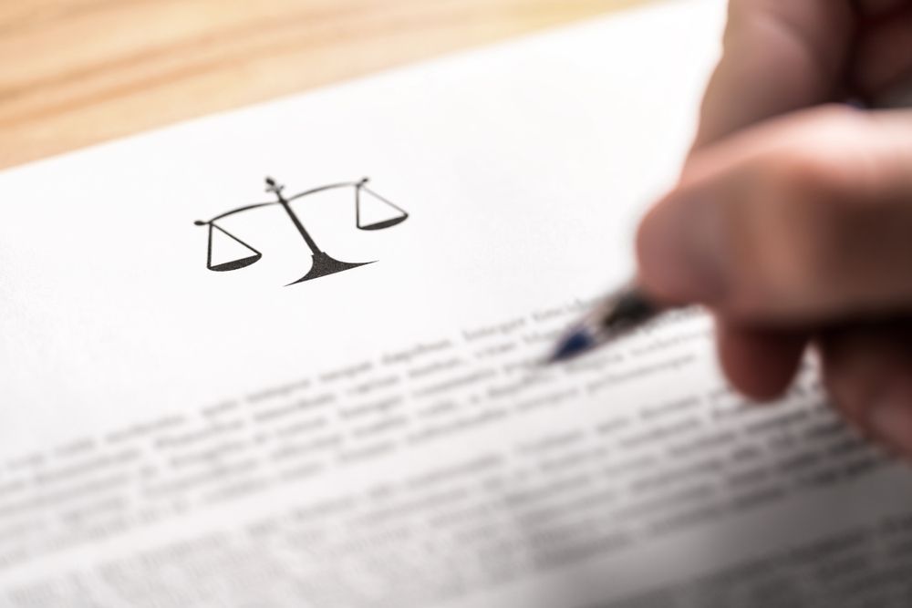 Person Signing Document With Scales of Justice Symbol — Trapski Family Law Geelong in Newtown, VIC