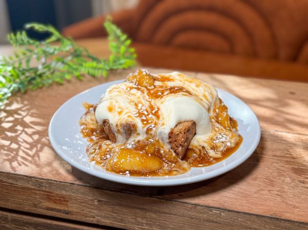 Plate of cinnamon roll with white icing and caramel sauce on a wooden table