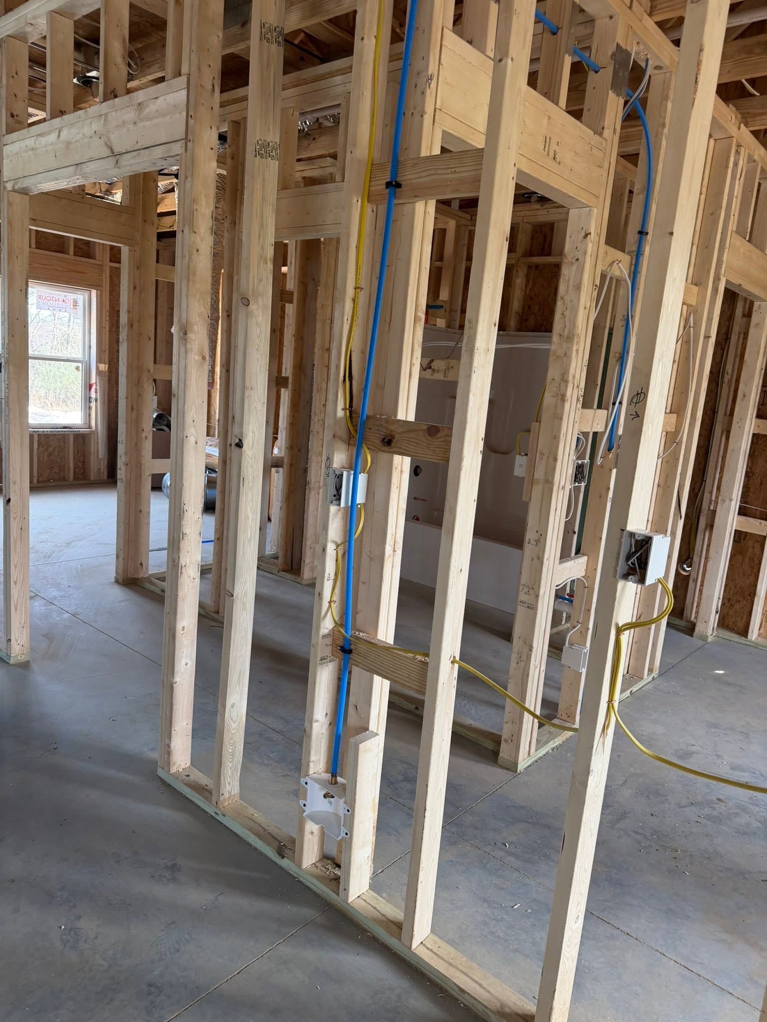 Interior of a house under construction with exposed wooden framing and a blue conduit pipe.