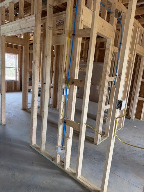 Interior of a house under construction with exposed wooden framing and a blue conduit pipe.