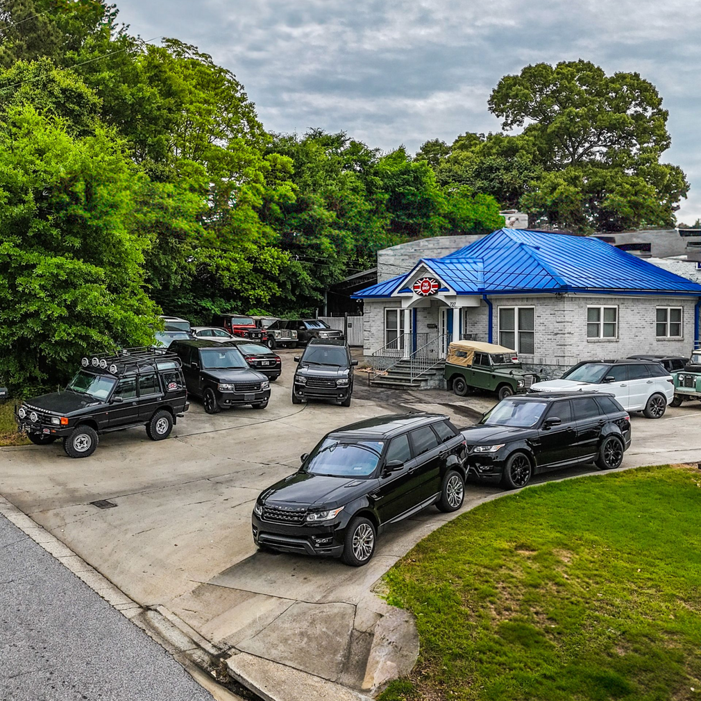 Two offroad cars are parked in a garage next to a table. | The Shop Norcross