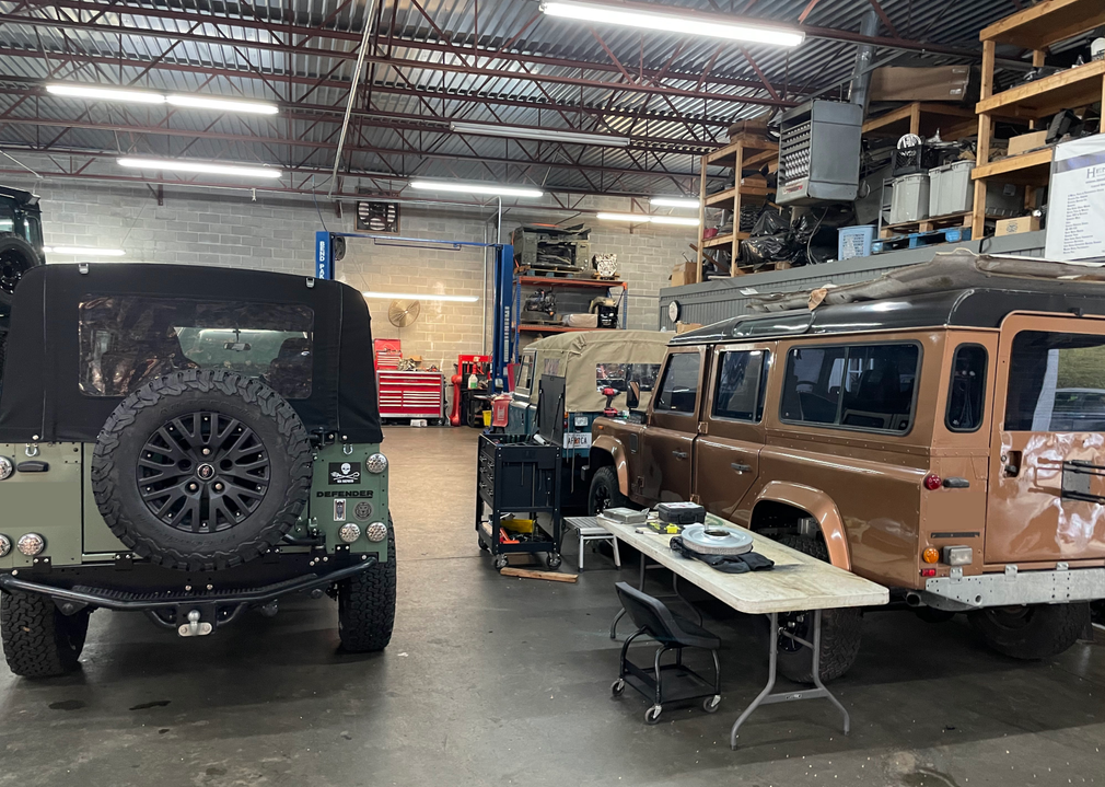 Two offroad cars are parked in a garage next to a table. | The Shop Norcross