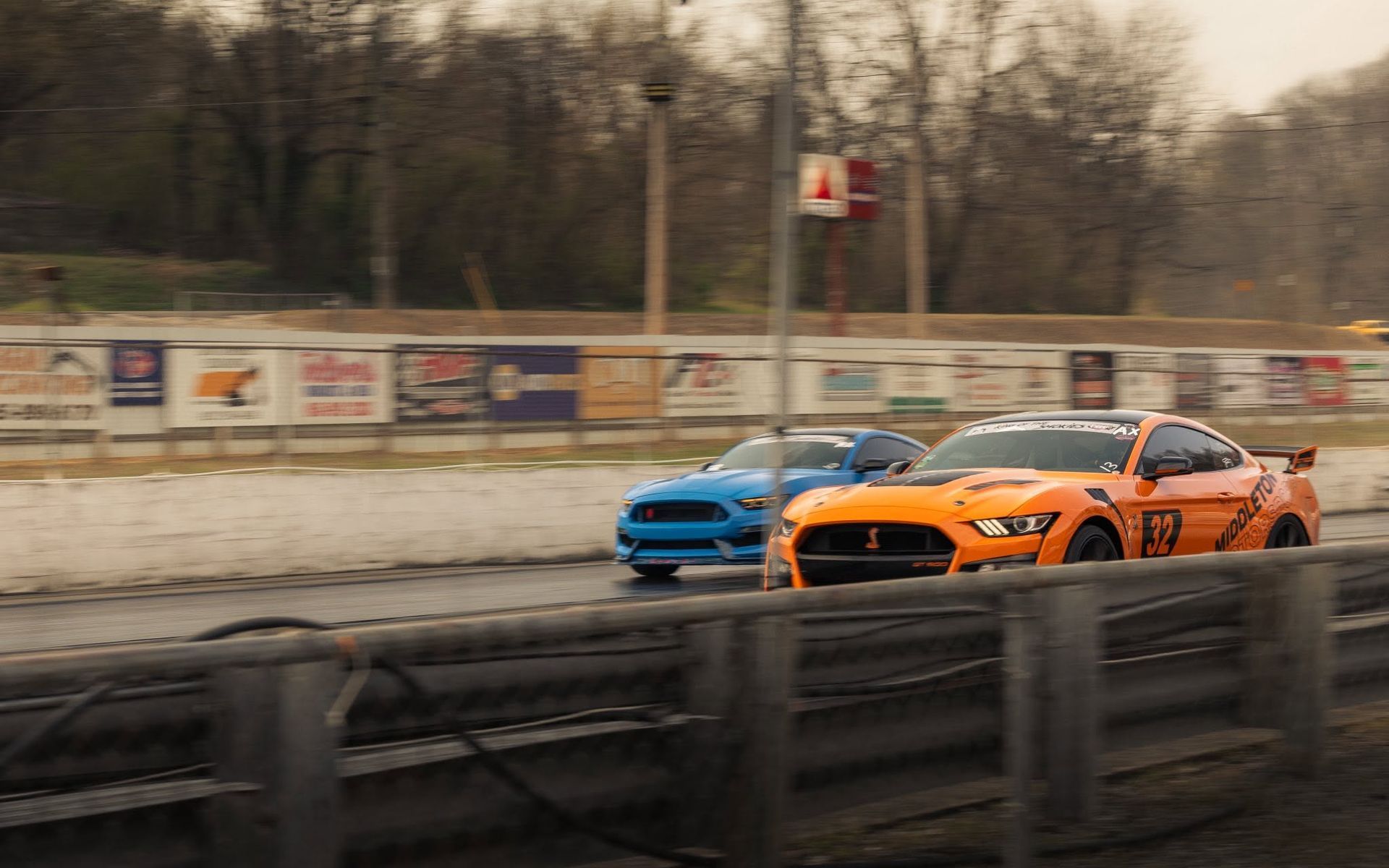 Two sports cars, blue and orange, racing side by side on a track.