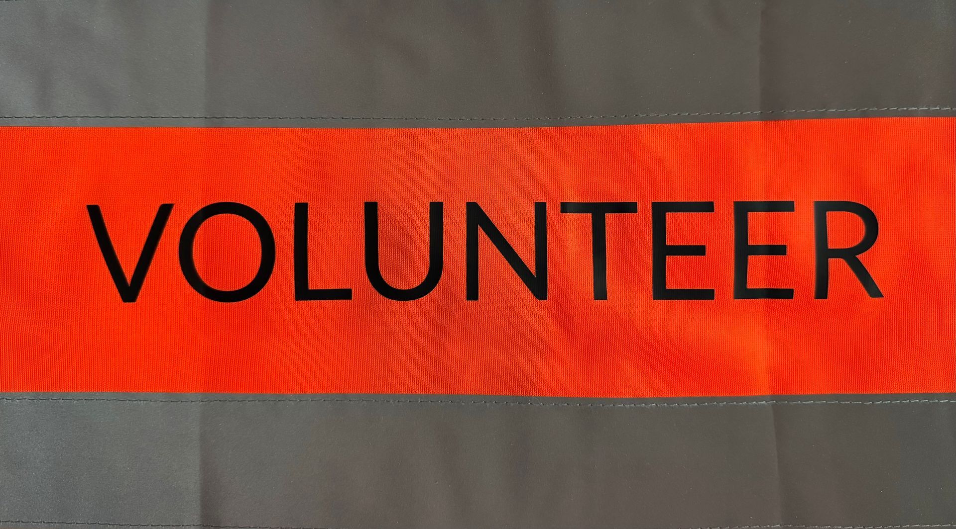 Black “VOLUNTEER” text on a red and gray banner.