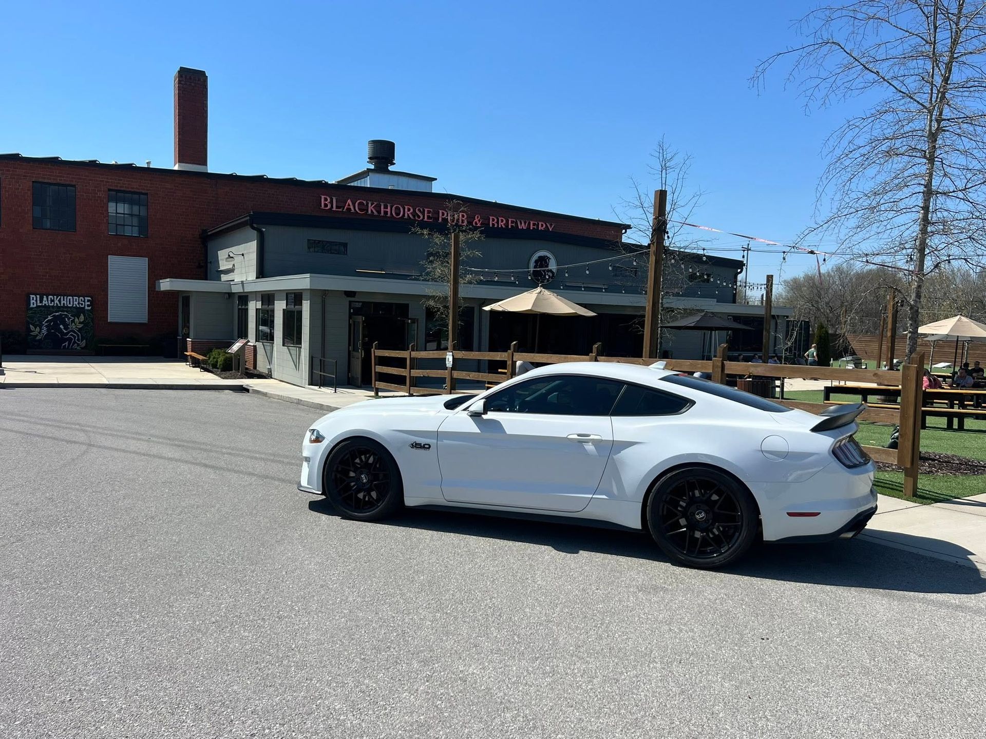 White sports car parked outside a red brick building with a covered entrance on a sunny day