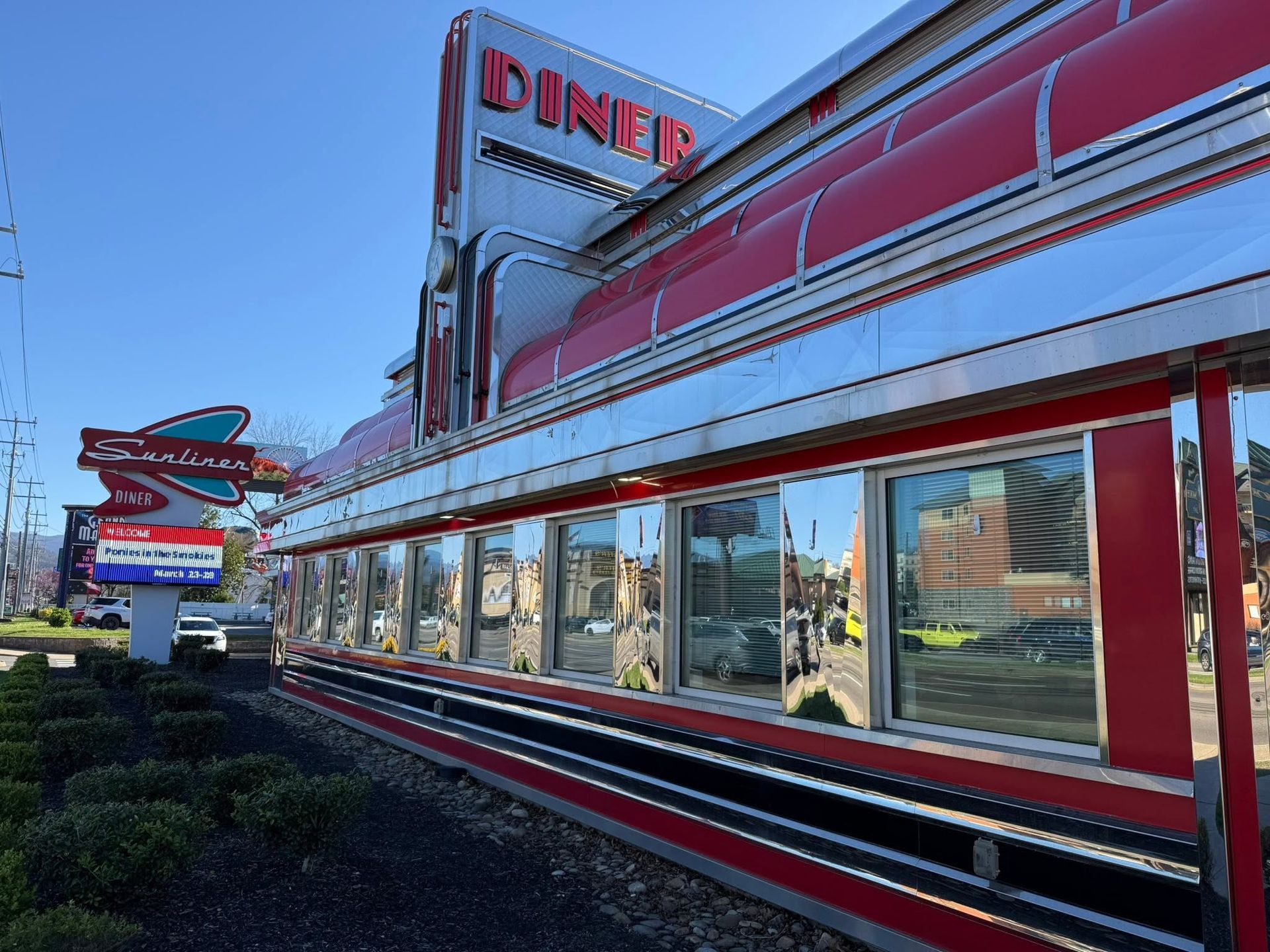 Red-and-silver retro diner exterior with large windows and rooftop sign at dusk