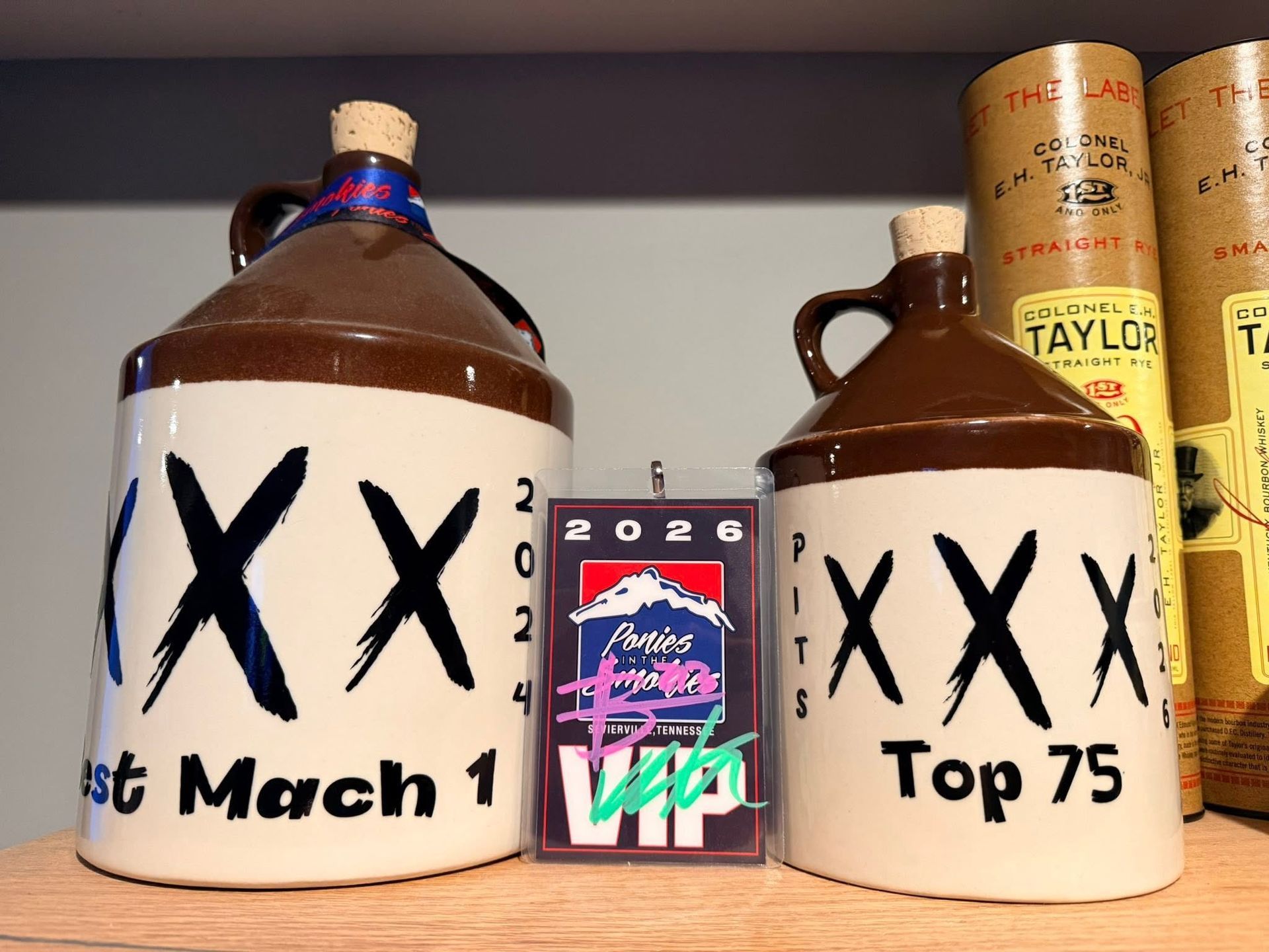 Two brown jugs labeled “XX” flanking a small 2026 sign, with bourbon bottles in the background.