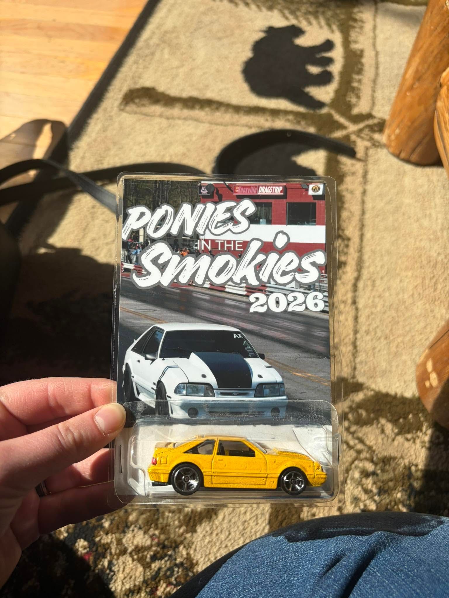 Hand holding a Road & Track Smokies 2024 magazine with a yellow car on the cover.