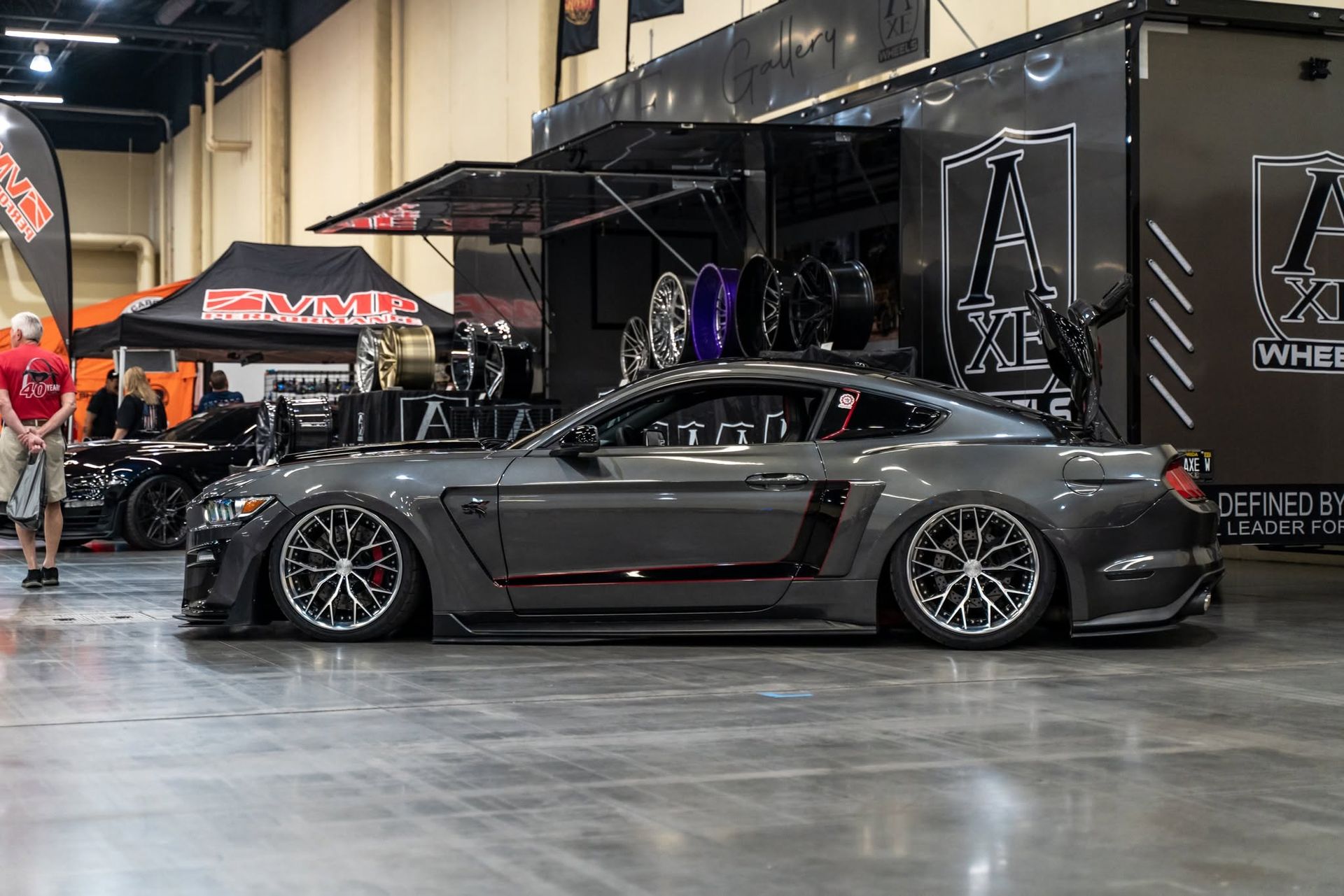 Low black sports car with purple accent lights at an indoor auto show