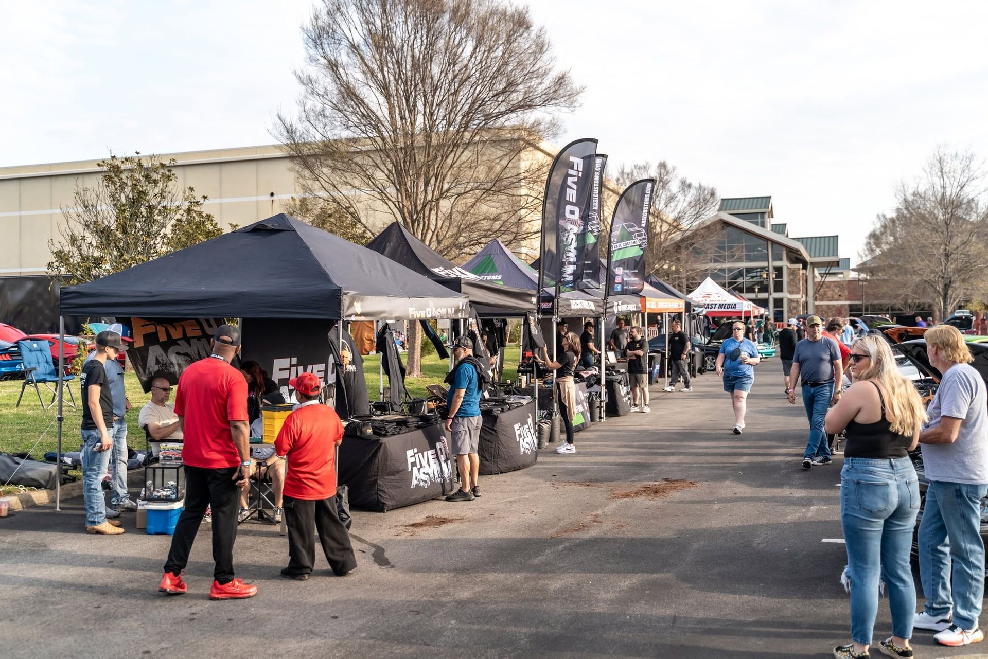 Outdoor market with vendor tents and people browsing along a paved walkway