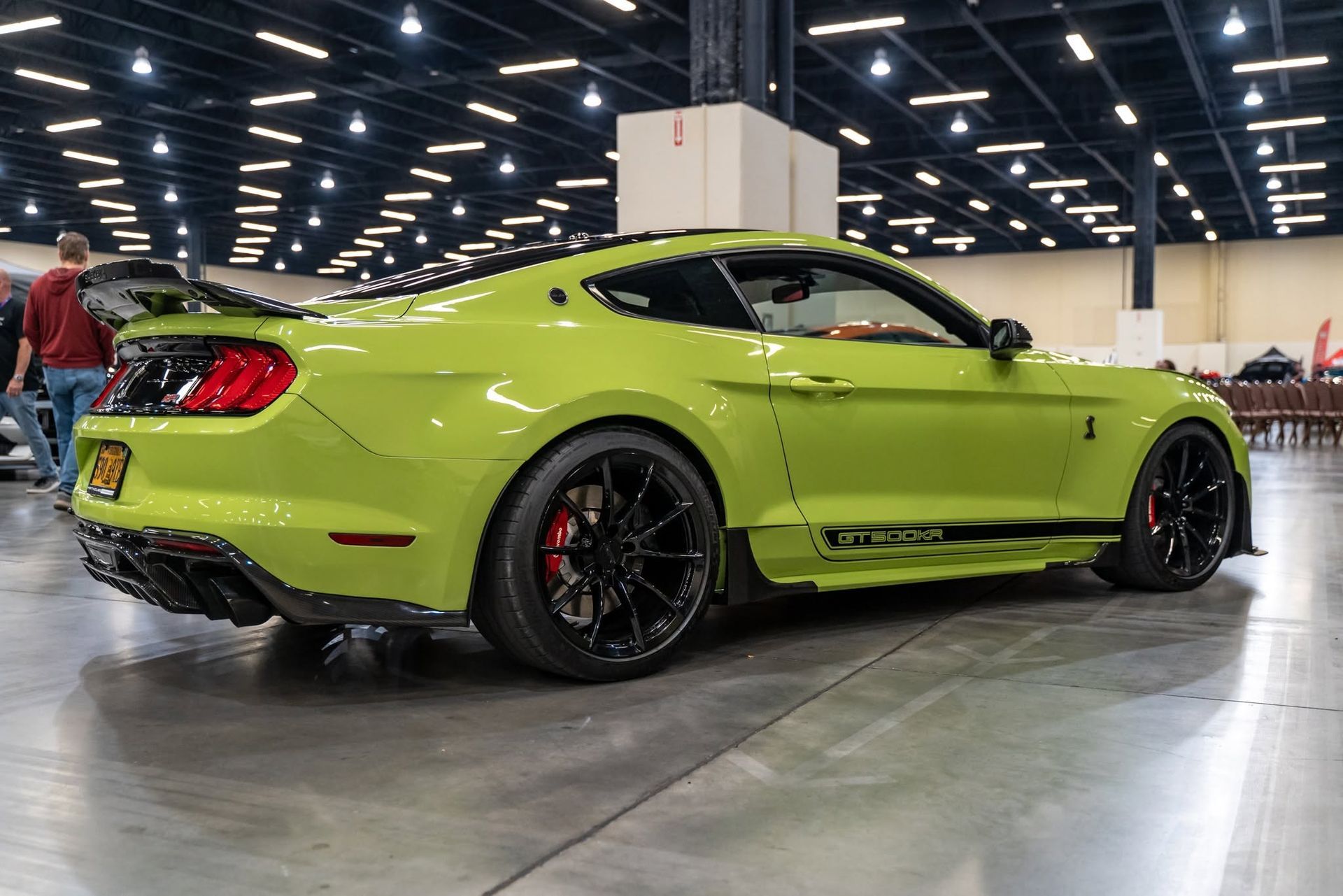 Bright lime green sports car at an indoor auto show, side view on polished floor