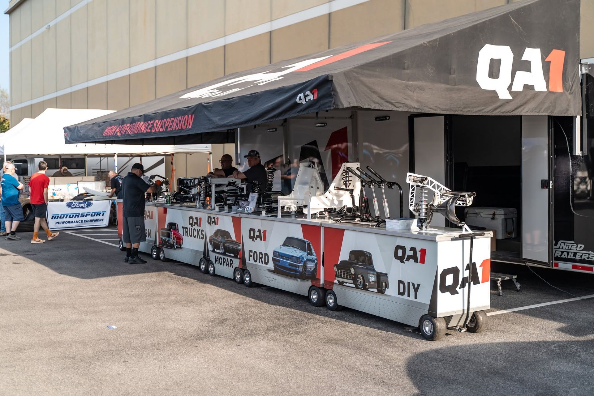 Outdoor Q1 DIY booth with tents, tools, and people at a motorsport event