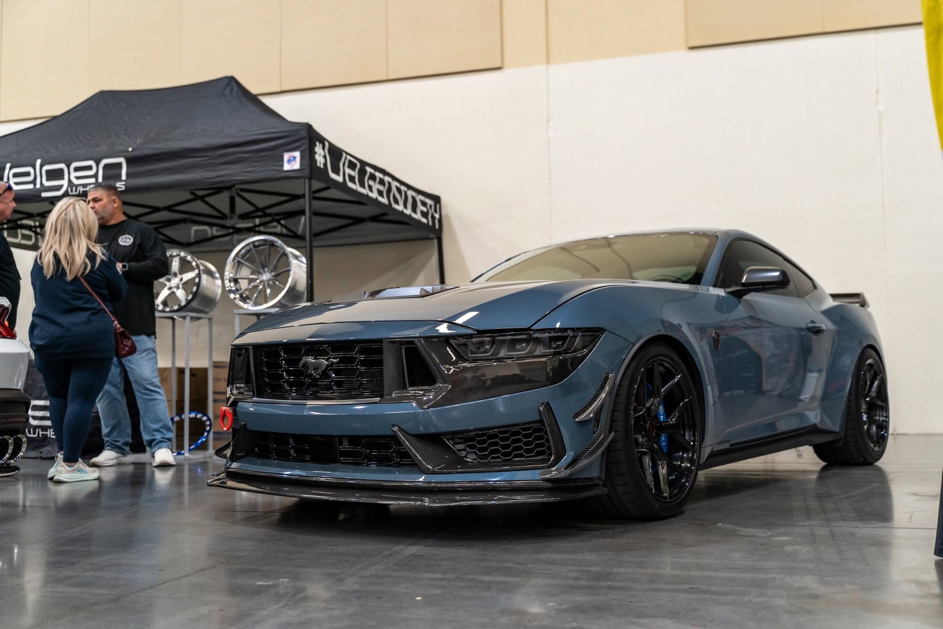 Custom dark blue sports car displayed at an indoor auto show booth