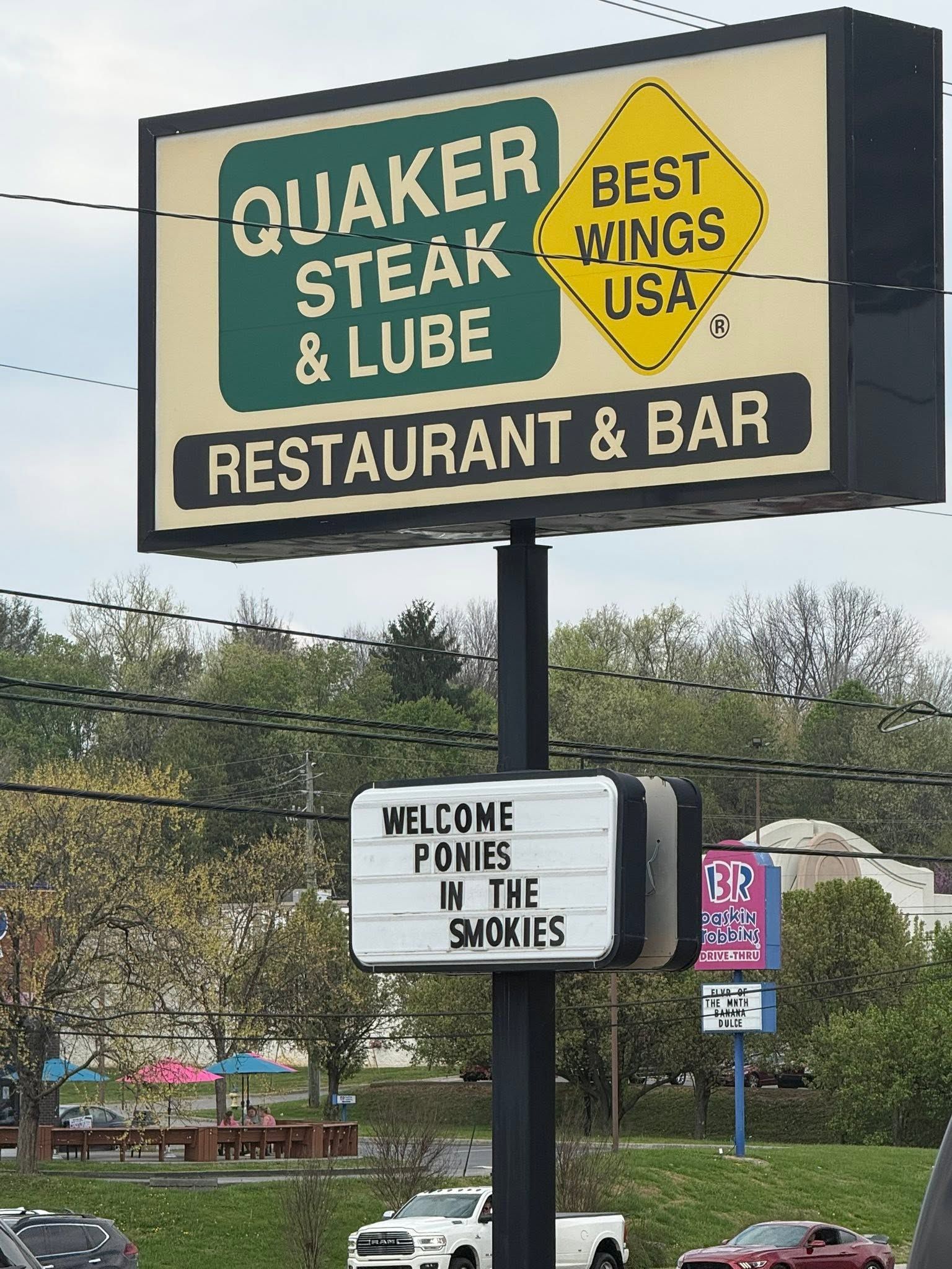 Quaker Steak & Lube restaurant sign advertising “Best Wings USA” with a “Welcome Home Police” notice below