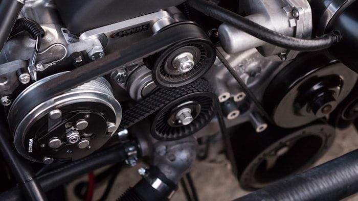 Close-up of a car engine with belts, pulleys, and metallic components exposed