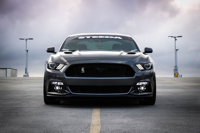 Front view of a black sports car on a runway under cloudy skies