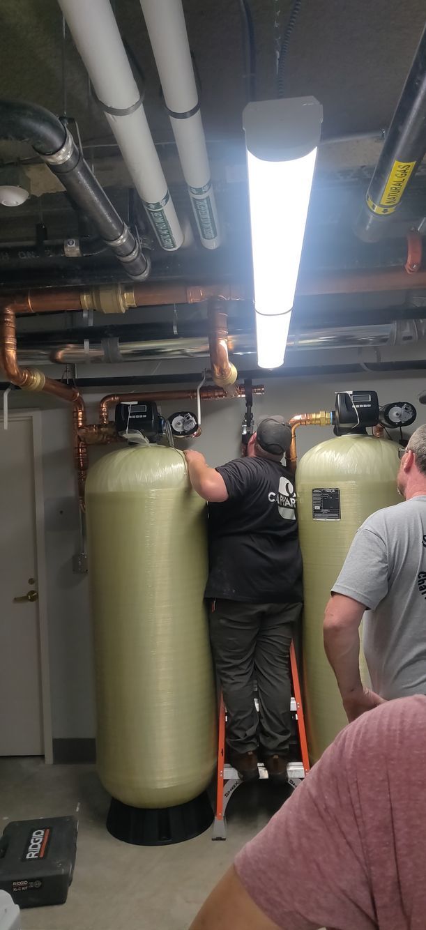 Two men are working on a water filter in a basement.