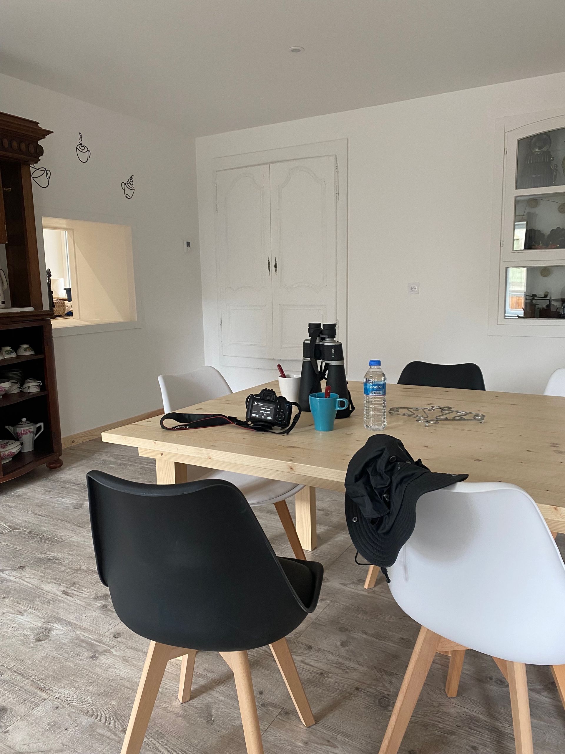 Une salle à manger avec une table et des chaises noires et blanches. Des objets sont posés sur la table.