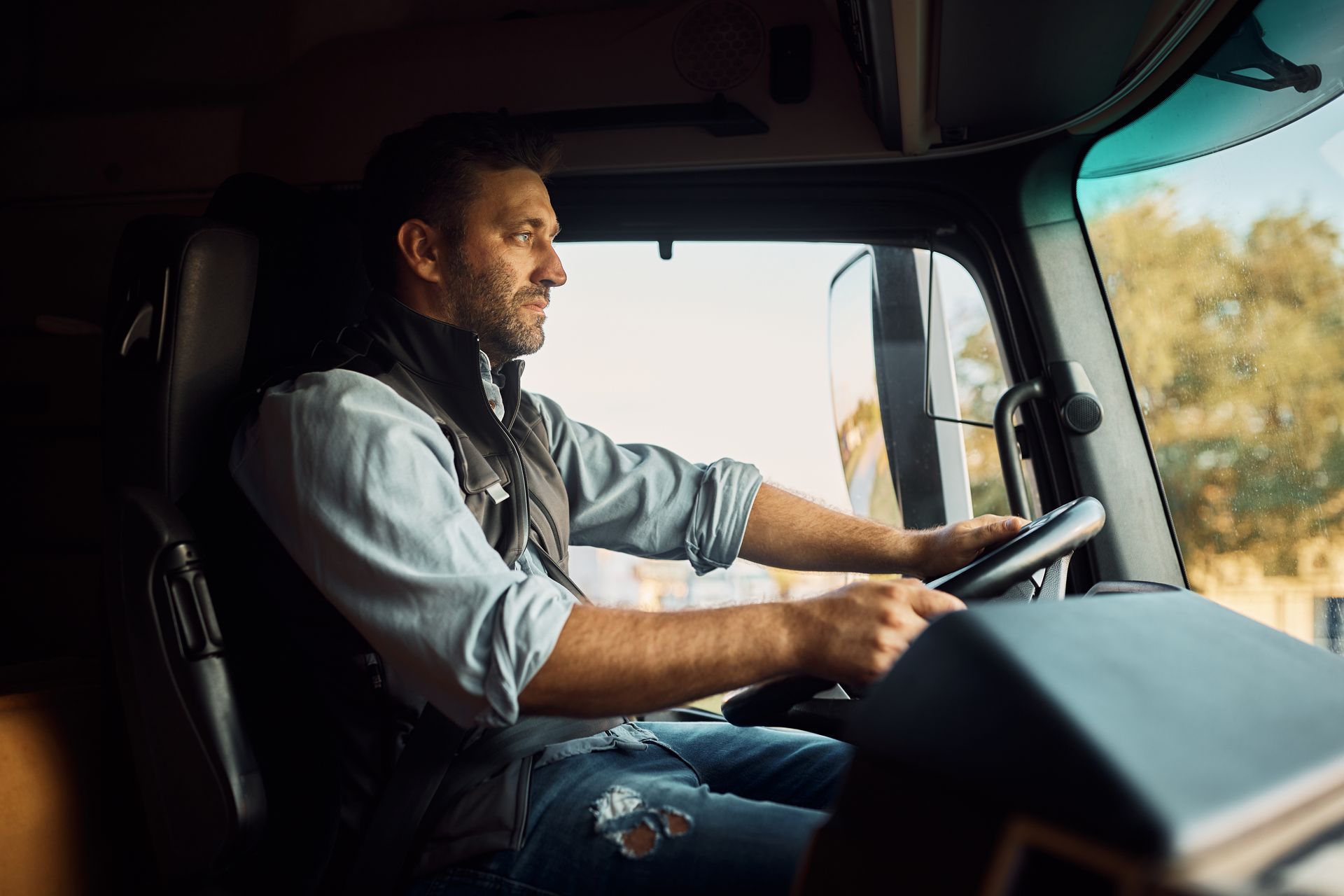 A man is sitting in the driver 's seat of a semi truck.