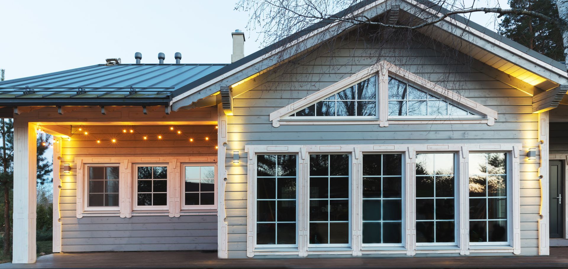 A house with a lot of windows and a roof is lit up at night.